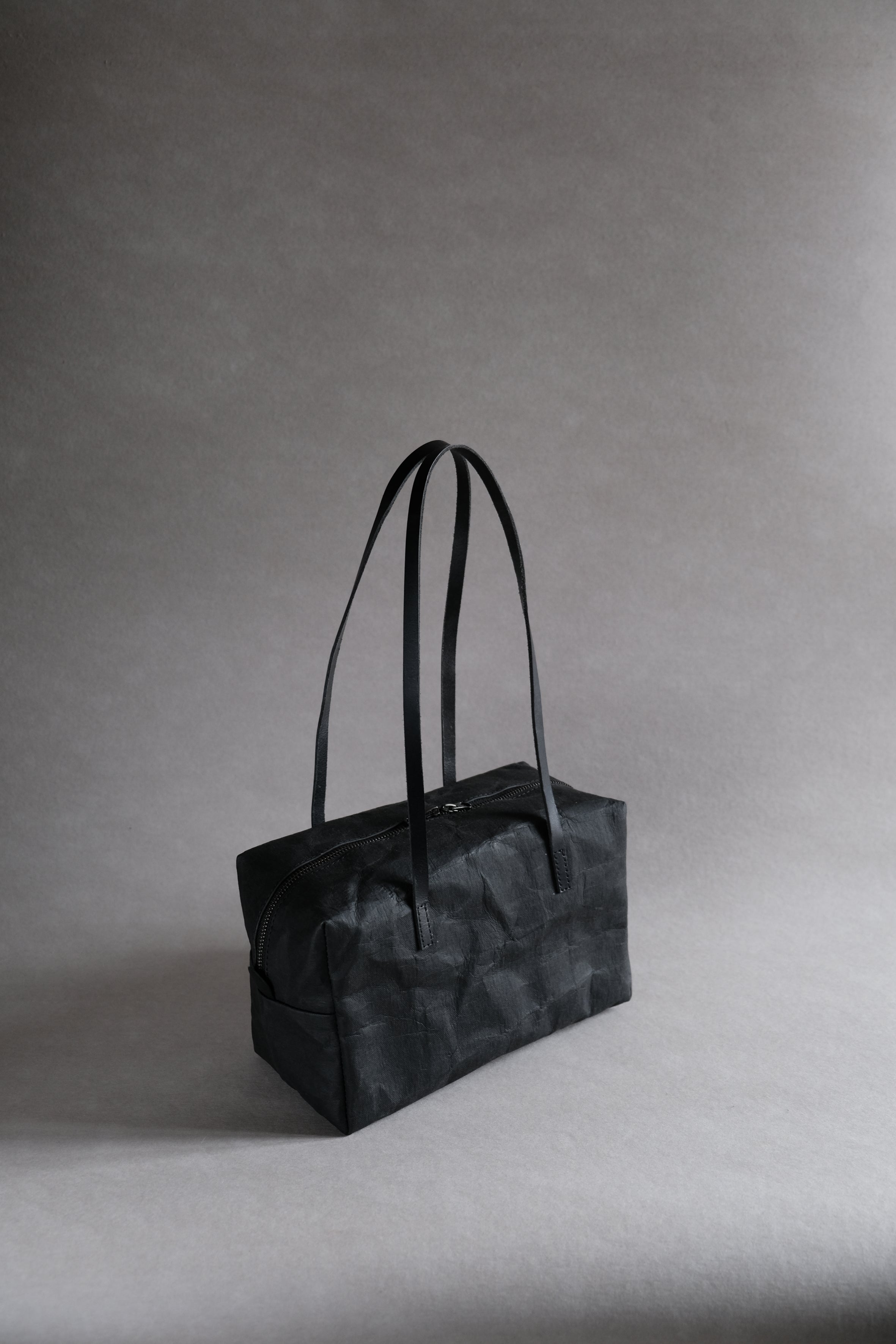 LangackerhäuslのミニボストンバッグBUDDY(バディ)。マットブラックの特殊加工紙が描く端正なフォルムと、13cmの広いマチによる実用性を兼ね備えた、オーストリア製ハンドメイドバッグ。