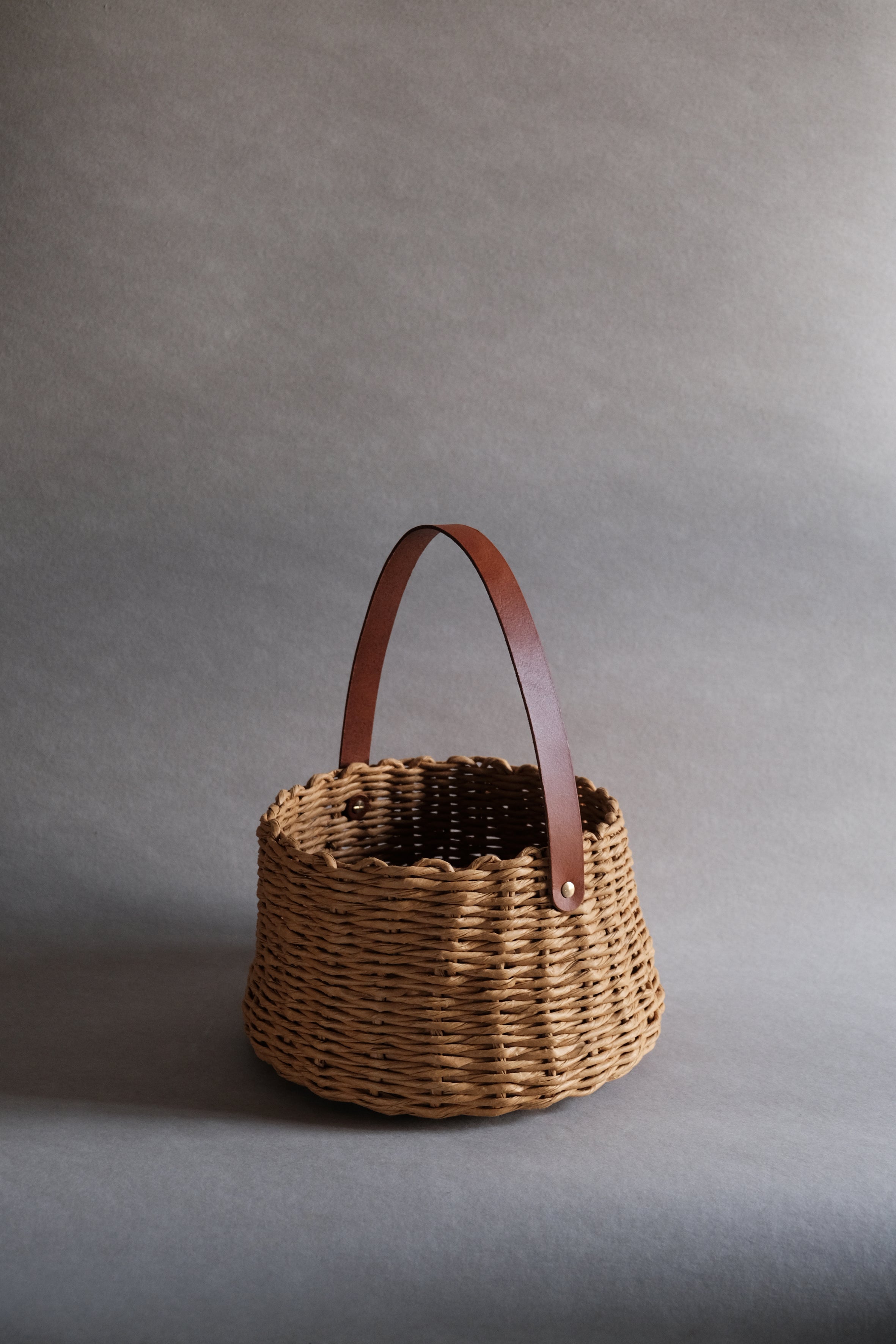 フランス製紙撚り糸をデザイナーが手編みしたCOCOON BASKET(コクーン バスケット)。丸みのある繭のようなフォルムと、真鍮金具で固定されたレザーハンドルが美しい、オーストリア製ハンドメイドのカゴバッグ。
