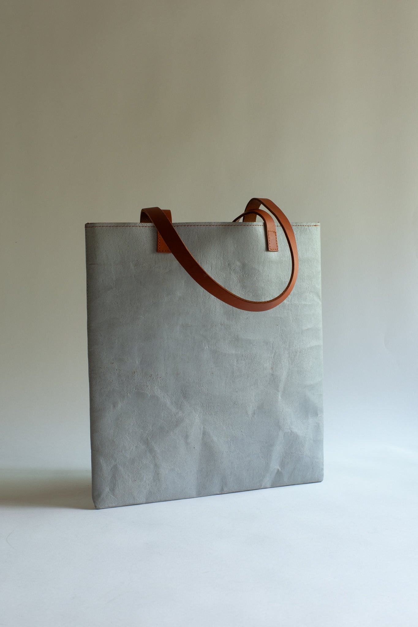 LangackerhäuslのコンクリートトートバッグSLEEVE(スリーブ)。コンクリートの質感と紙の柔軟性を併せ持つ独創的な素材を使用し、長いレザーハンドルがアクセントを添えるオーストリア製ハンドメイド縦型トート。