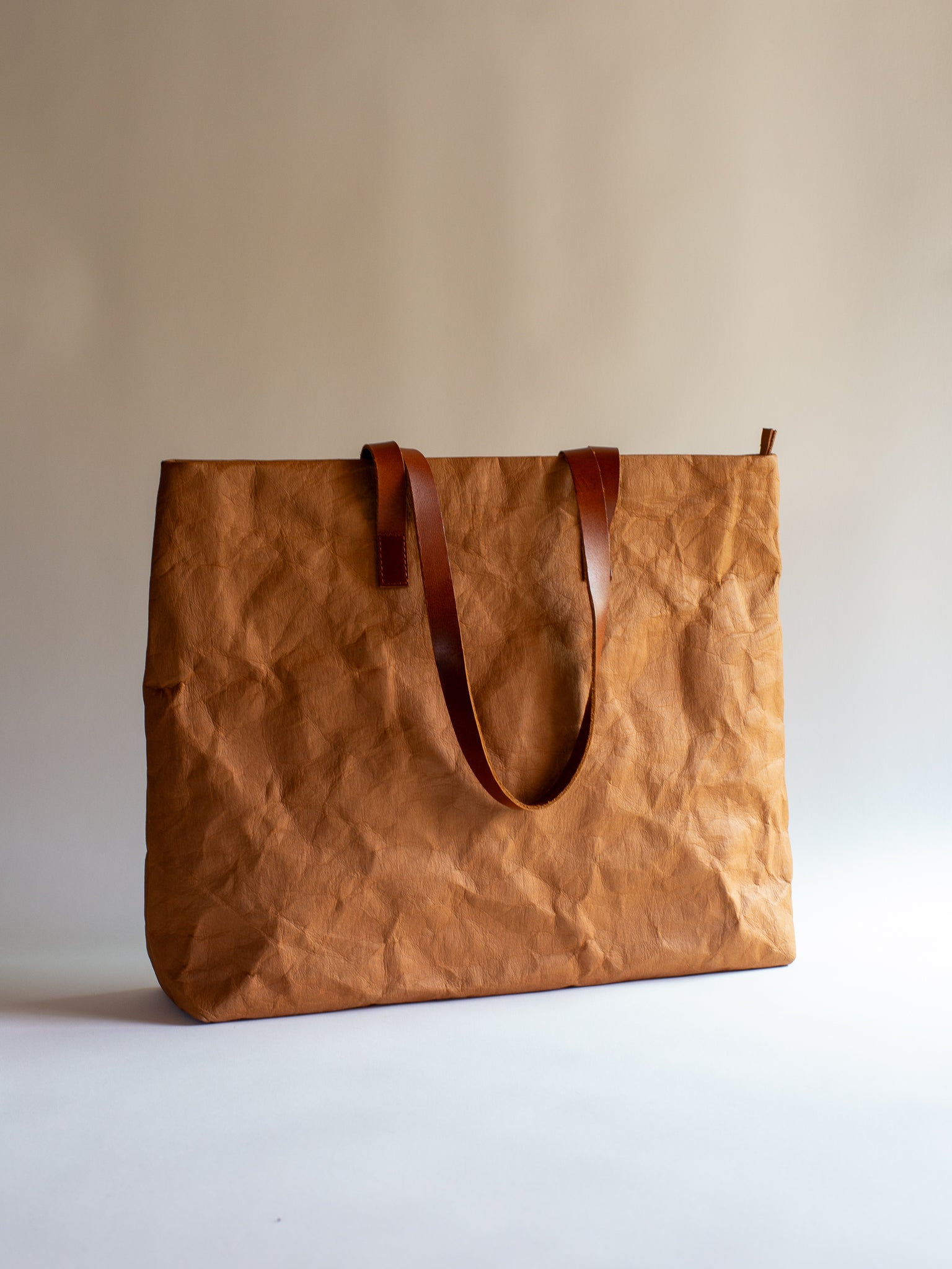 Langackerhäuslの草木染めビッグトートTRANSPORTER(トランスポーター)。タバックカラーの特殊加工紙とレザーストラップが調和する、圧倒的なサイズ感と軽さを両立したオーストリア製ハンドメイドバッグ。