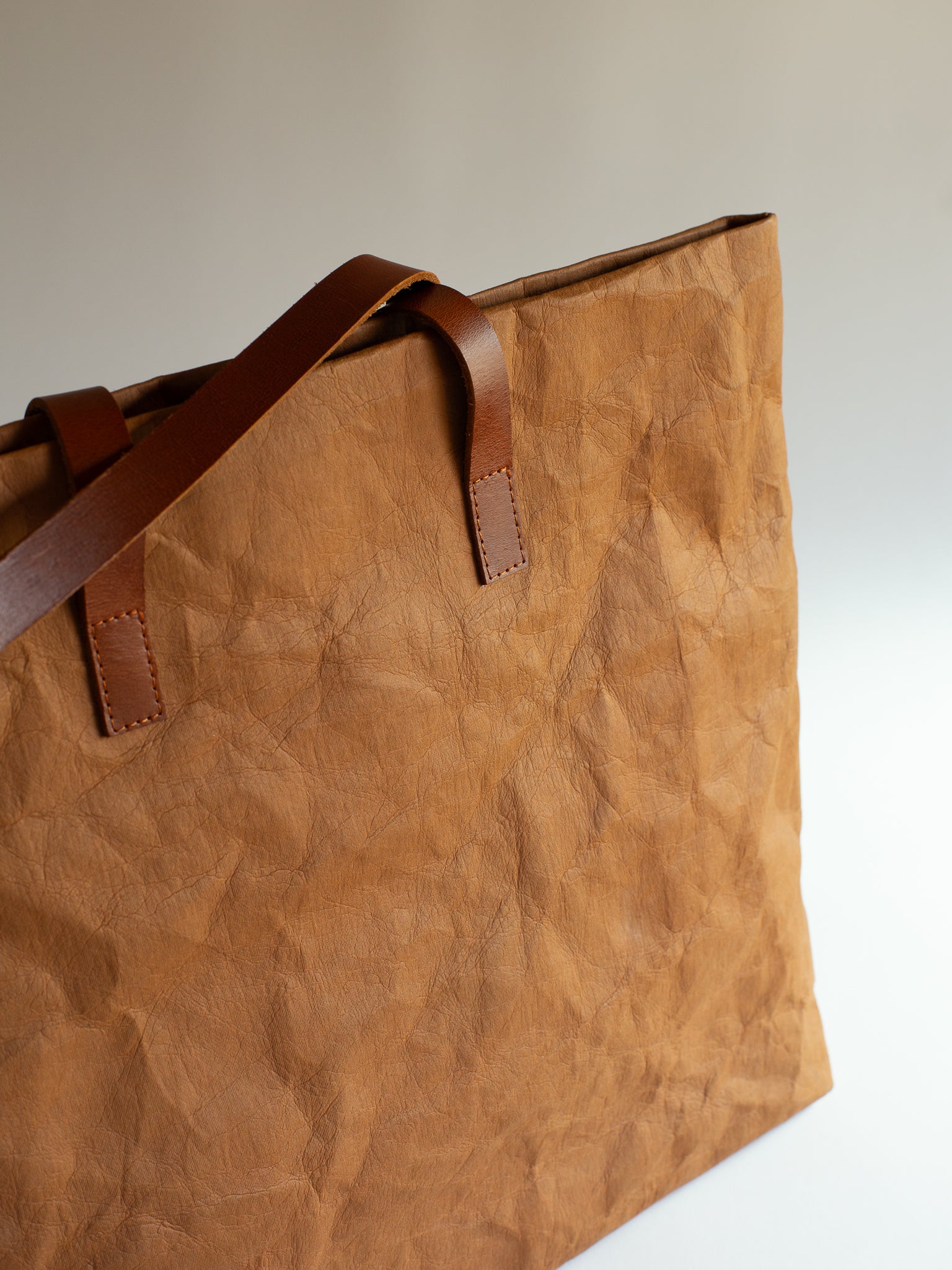 Langackerhäuslの草木染めビッグトートTRANSPORTER(トランスポーター)。タバックカラーの特殊加工紙とレザーストラップが調和する、圧倒的なサイズ感と軽さを両立したオーストリア製ハンドメイドバッグ。