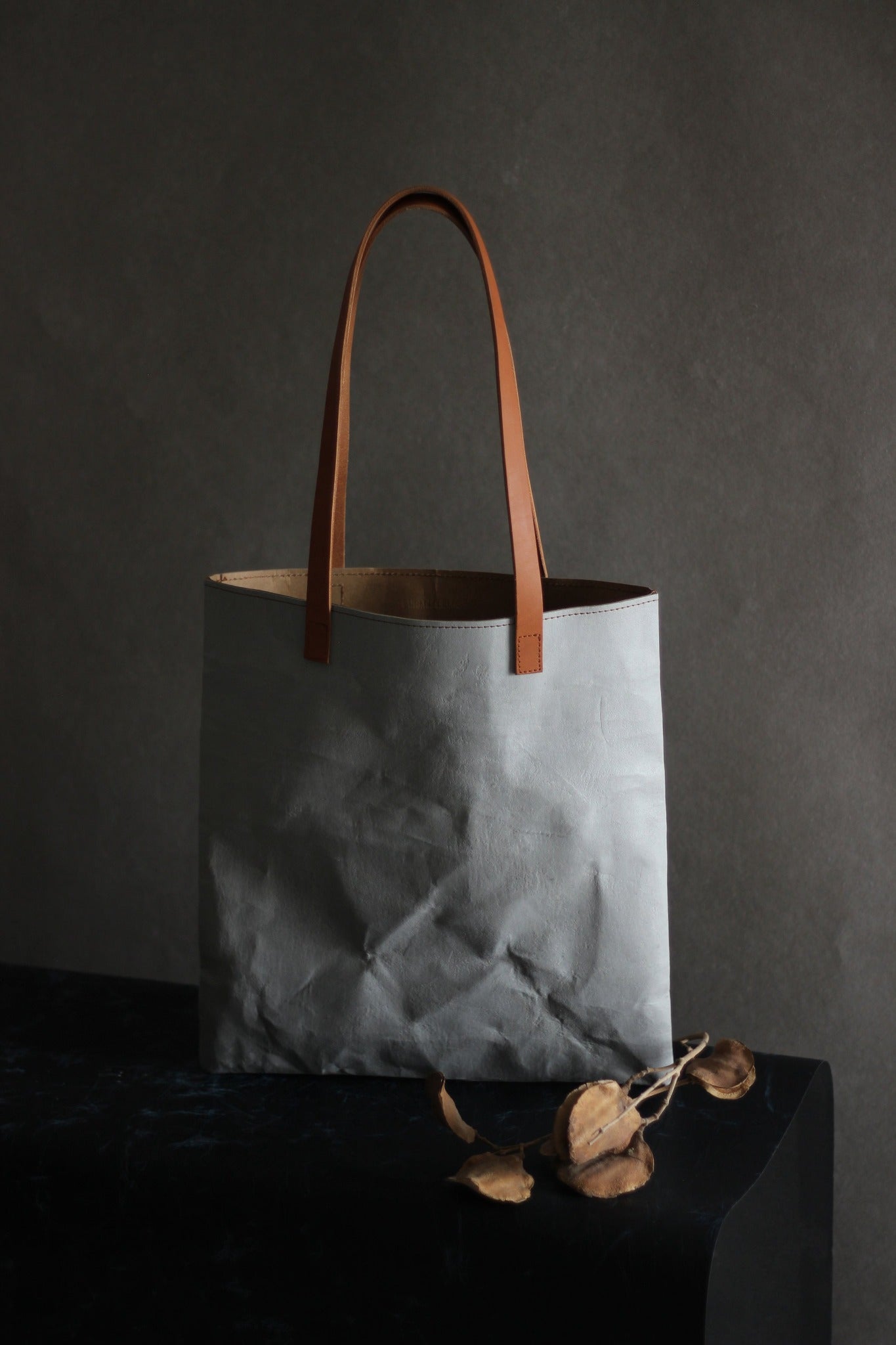 LangackerhäuslのコンクリートトートバッグSLEEVE(スリーブ)。コンクリートの質感と紙の柔軟性を併せ持つ独創的な素材を使用し、長いレザーハンドルがアクセントを添えるオーストリア製ハンドメイド縦型トート。