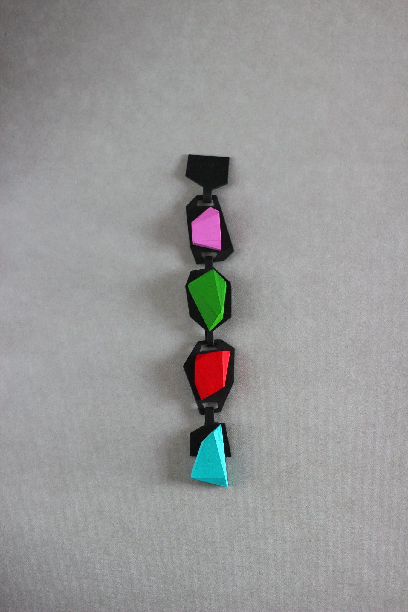 Langackerhäuslの身に纏うアート「KRISTL(クリストル)」ブレスレット。ブラックのベースにネオングリーンやピンクの幾何学的な結晶が並ぶ、ハンドペイントが施された超軽量な磁石開閉式バングル。