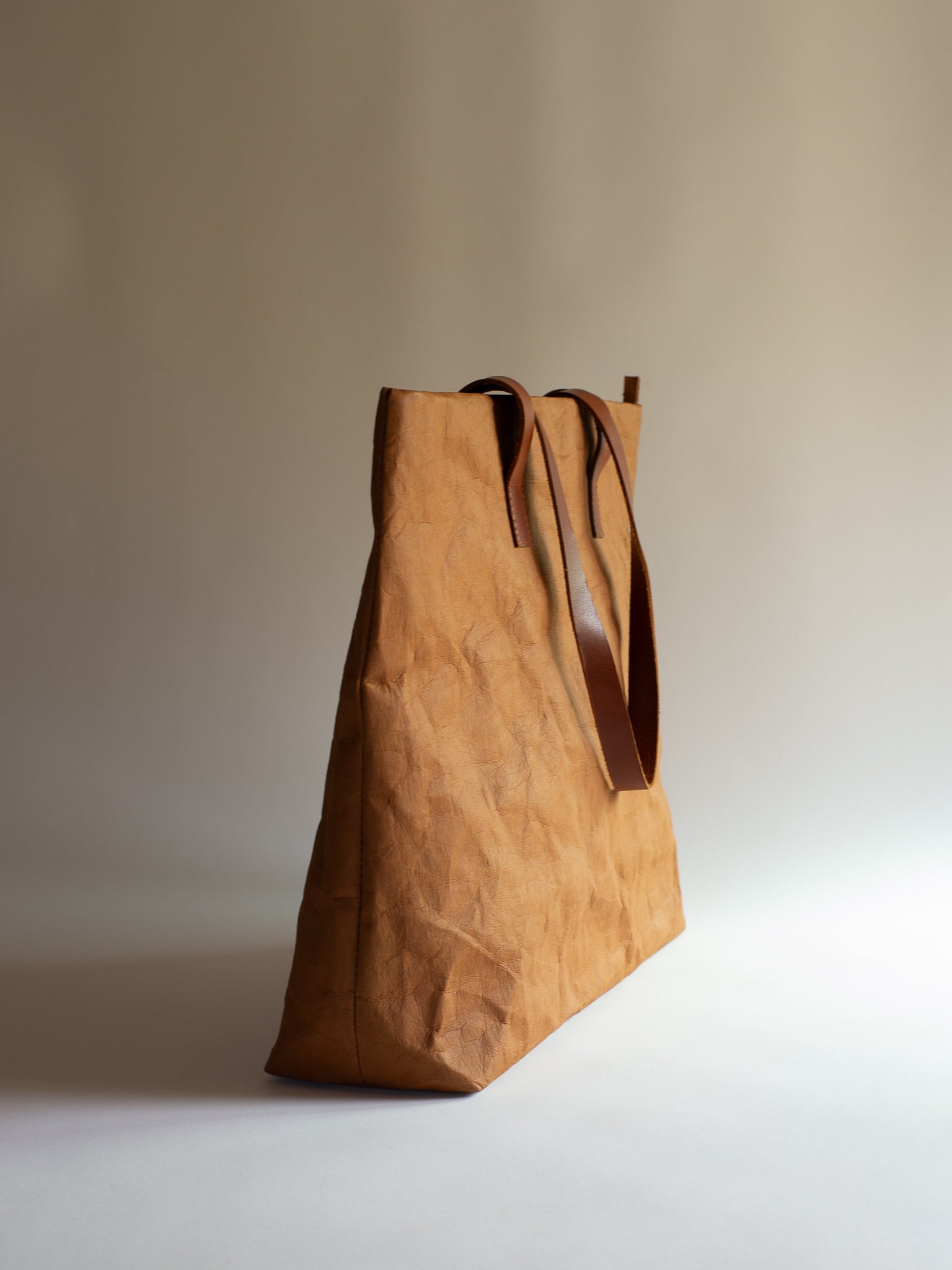Langackerhäuslの草木染めビッグトートTRANSPORTER（トランスポーター）。タバックカラーの特殊加工紙とレザーストラップが調和する、圧倒的なサイズ感と軽さを両立したオーストリア製ハンドメイドバッグ。